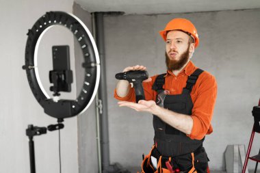 İnşaatçı, elektrikli tornavidayla video kaydı yapıyor, tadilat dairesinde çalışıyor. Boşluğu kopyala