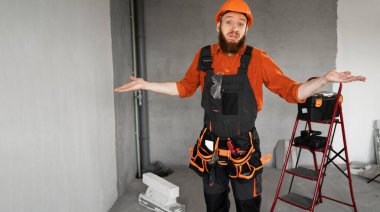 Turuncu şapka takan yakışıklı genç adam kollarını kaldırmış ve kafası karışmış. Şüpheli bir kavram. Pankart. Boşluğu kopyala