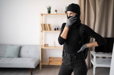 Kara kar maskeli dalgın bir hırsız ya da evde kameraya bakarak para çalan bir soyguncu. Boşluğu kopyala