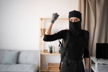 Siyah kar maskeli bir hırsız ya da soyguncu terör suçlusu evde para çalıyor yumrukluyor, jest yapıyor, kameraya bakıyor. Boşluğu kopyala