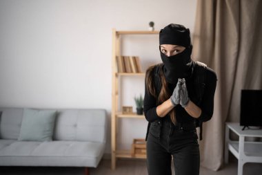 Hırsızlık ve suç. Yardım Konsepti. Hırsız ya da davetsiz misafir kadın, siyah kar maskesi takmış ve yardım eli uzatıyor. Boşluğu kopyala