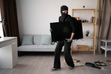 Siyah kar maskeli kadın hırsız evden televizyon çalıyor. Soygun terörü