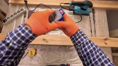 Bir adamın atölyedeki kablosuz tornavidayı matkapla deldiği pov çekimi. DIY projesi ve marangozluk hobisi için araç hazırlama.