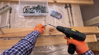 POV, ahşap bir kalasa metal parantez takmak için kablosuz tornavida kullanan birini yakına çekiyor. DIY ev montaj ve inşaat konsepti.
