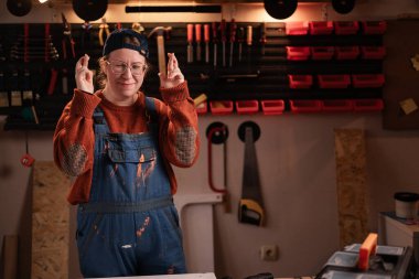 Çalışan kadın, atölye sahnesinde atölye kıyafetleri giyer. Duvarda asılı duran el kol hareketleriyle. Bayan marangoz gece geç saatlerde otantik garajda. Boşluğu kopyala