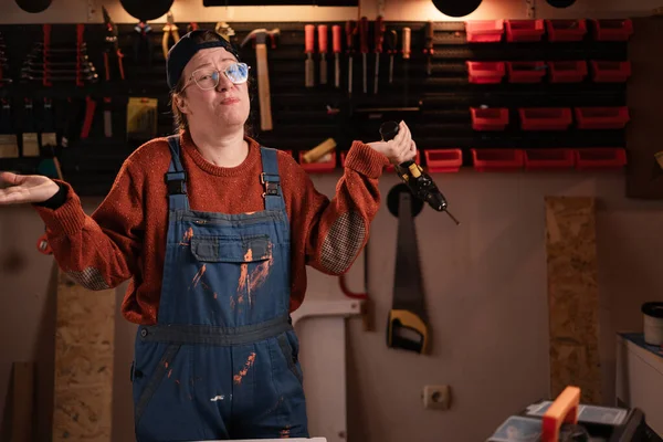 Çalışan kadın atölye sahnesinde atölye kıyafetleri giyer ve duvarda asılı aletler vardır. Kameraya cevap ile bakamadığımı söyler. Bayan marangoz gece geç saatlerde otantik garajda. Boşluğu kopyala