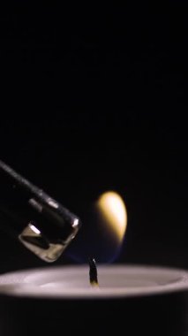 Yavaş çekim çakmağı koyu arkaplanda Candle 'da alev alev yanıyor. dikey video