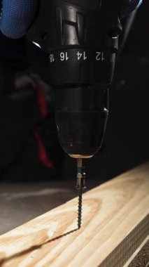 Tahta tahtayı matkapla vidalayan ahşap işçisini kapatın. Makro. Dikey video