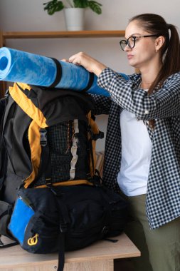 Sırt çantalı kadın ev içi seyahati için sırt çantasını hazırlıyor. Boşluğu kopyala