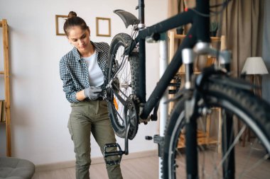 Evde bisiklet tamir eden genç bir kadın. Boşluğu kopyala