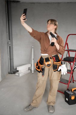 Kameralı telefonda matkapla selfie çeken kadının portresi. Boşluğu kopyala