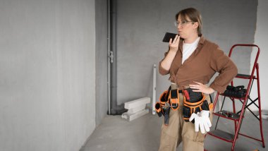 Akıllı telefonda ses komutunu kullanan kadın tamirci tadilattan önce boş bir odada duruyor. meslek, inşaat ve inşaat kavramı.