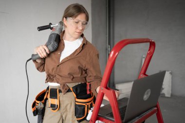 Onarım, geliştirme ve yeniden inşa konsepti. Evde tamir ve onarım yapan dizüstü bilgisayarı olan bir kadın tamirci. Boşluğu kopyala