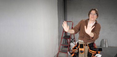 Elinden her iş gelen alet kemeri takan genç bir kadın el kaldırıyor ve hayır, teşekkür ederim. Kes şunu. Pankart. Boşluğu kopyala