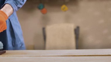 Turuncu eldivenli, elektrikli zımpara makinesiyle çalışan erkeklerin yakın çekimi. Boşluğu kopyala