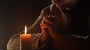 Yakından yanan bir mumla dua eden bir adam. Din kavramı