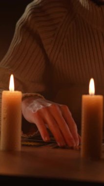 Adam falcı elinde mumlarla tarot kartlarını anlatıyor, yakın plan. dikey video