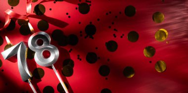 Doğum günü ve yıldönümü kutlaması kavramı. 78 numara, büyük altın konfetiyle kırmızı arka planda 78 gümüş kutlama doğum günü mumu. 78 'inci yaş günü. düz yat