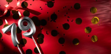 Doğum günü ve yıldönümü kutlaması kavramı. 79 numara, büyük altın konfetiyle şenlikli kırmızı arka planda 79 gümüş kutlamalı doğum günü mumu. 79 'uncu yaş günü. düz yat