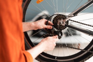 Bisiklet tekerleğinin dişlilerini ayarlayan erkek ellerini kapat. Ulaşım bakımı ve bisiklet servisi kavramı