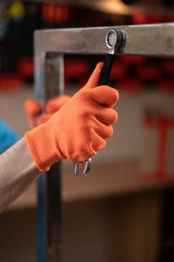 Atölyedeki metal bir yapının sürgüsünü sıkmak için ingiliz anahtarı olan erkek eller. Sanatçılık kavramı.