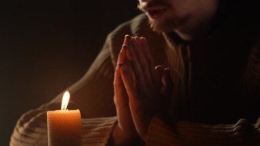 Elleri yanan bir mumla dua ederek bağlanmış bir adama yaklaş. İnanç, din ve ruhani bağlılık kavramı. Umut ve meditasyon kutsal bir sessizlik ve tapınma anında.