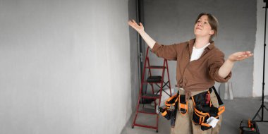 Gülümseyen duygusal işçi kadın yeni evde alet kemeri takıyor. Yenileme dairesi. Ev konseptini onar. Boşluğu kopyala