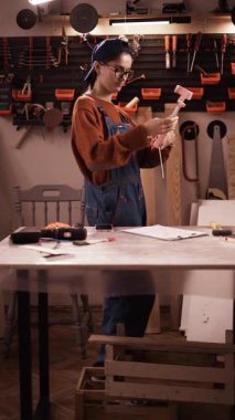 Kapaklı kadın blogcu tamirci, üç ayaklı telefon ile ev garajı atölyesinde diy video kaydetmek için hazırlanıyor. Dikey video