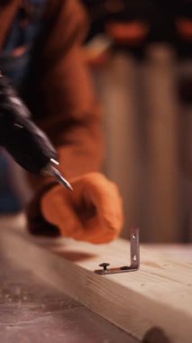 Ağaç vidalarını sökmek için kadın ellerini kablosuz elektrikli matkapla eldivenle kapatın. Dikey video