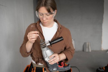 Tadilat projesinde matkap tabancası olan kadın işçi. Boşluğu kopyala