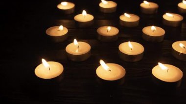 Koyu siyah arkaplanda birçok yanan mum, yakın plan