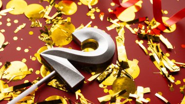 Kırmızı bayramda konfeti arkaplanlı 2 numaralı doğum günü rakamı. İki yıllık doğum günü. Doğum günü, yıldönümü ve tarih kavramı. yakın plan