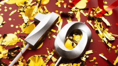 Kırmızı bayramda konfeti arkaplanlı 10 numaralı doğum günü rakamı. 10 'uncu yaş günü. Doğum günü, yıldönümü ve tarih kavramı. yakın plan