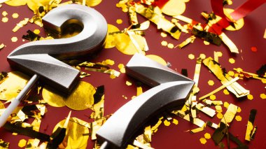 Kırmızı bayramda konfeti arkaplanlı 27 numaralı doğum günü rakamı. Yirmiyedinci yaş günü. Doğum günü, yıldönümü ve tarih kavramı. yakın plan