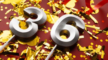 Kırmızı bayramda konfeti arkaplanlı 36 numaralı doğum günü rakamı. 36 'ncı yaş günü. Doğum günü, yıldönümü ve tarih kavramı. yakın plan