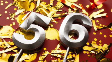 Kırmızı bayramda konfeti arkaplanlı 56 numaralı doğum günü rakamı. 56 'ncı yaş günü. Doğum günü, yıldönümü ve tarih kavramı. yakın plan
