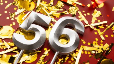 Kırmızı bayramda konfeti arkaplanlı 56 numaralı doğum günü rakamı. 56 'ncı yaş günü. Doğum günü, yıldönümü ve tarih kavramı. yakın plan