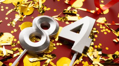 84 numaralı kırmızı şenlik kutlamasında konfeti arka planında. Seksen dört yaş günü. Doğum günü, yıldönümü ve tarih kavramı. Boşluğu kopyala