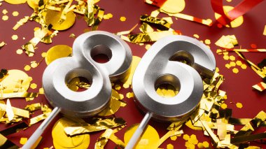 Kırmızı şenlik programında 86 numaralı doğum günü rakamı konfeti arka planında. Seksen altı yaş günü. Doğum günü, yıldönümü ve tarih kavramı. Boşluğu kopyala