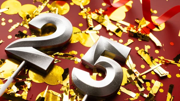 Kırmızı şenlikte konfeti arka planında 25 numaralı doğum günü rakamı. 25 'inci yaş günü. Doğum günü, yıldönümü ve tarih kavramı. yakın plan