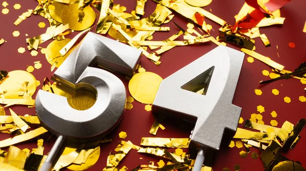 Kırmızı bayramda konfeti arkaplanlı 54 numaralı doğum günü rakamı. 54 'üncü yaş günü. Doğum günü, yıldönümü ve tarih kavramı. yakın plan