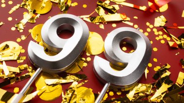 Kırmızı şenlikte konfeti arkaplanlı 99 numaralı doğum günü rakamı. Doksan dokuz yaş günü. Doğum günü, yıldönümü ve tarih kavramı. Boşluğu kopyala