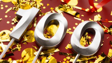 Kırmızı bayramda konfeti arkaplanlı 100 numaralı doğum günü rakamı. 100 yıllık doğum günü. Doğum günü, yıldönümü ve tarih kavramı. Boşluğu kopyala