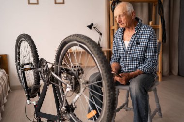 Eski bir bisikletçi bozuk bir bisikletin yanında oturuyor ve onarımları düşünüyor. Boşluğu kopyala