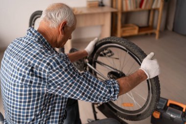 Kıdemli yaşlı adam evde hasarlı bisikletini tamir etti ve bakımını yaptı. Boşluğu kopyala