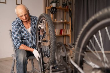 Kıdemli yaşlı adam evde hasarlı bisikletini tamir etti ve bakımını yaptı. Boşluğu kopyala