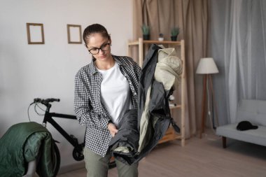 Yürüyüş, yürüyüş, kamp ve gezi konsepti. Genç bayan gezgin kamp çadırını katlıyor ve eve dönüş yolculuğuna hazırlanıyor. Kadın yürüyüşçü aktif bir hayat sürüyor ve tatile hazır..