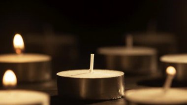 Çakmak, zifiri karanlıkta küçük çay ışıkları mumları yakıyor. Yakın plan. Romantik konsept