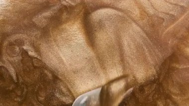 Küçük spatulalı altın sıvı doku lekeleri. Altın metalik boya, dudak parlatıcısı, oje, makyaj. en üstteki görünüm