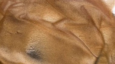 Küçük metal bir spatula kullanarak altın sıvı dudak parlatıcısı ya da tırnak cilası karıştırmak. Altın parıltılı arkaplan